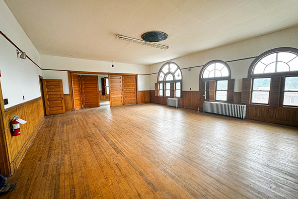 The third-floor ballroom: a wide bare wood floor, wainscoting and arched windows